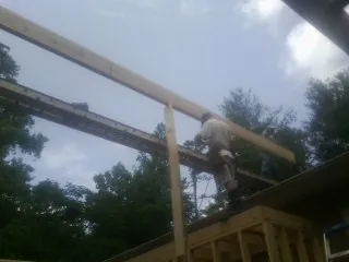 Carpenter setting a ridge beam over a new addition frame — Ice Dam Removal by Roofing Brothers in Holmen