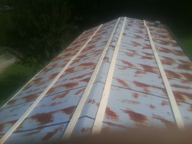 Rusted metal roof panels with new wood purlins before replacement — Storm Damage Roof Repair in Holmen by Roofing Brothers