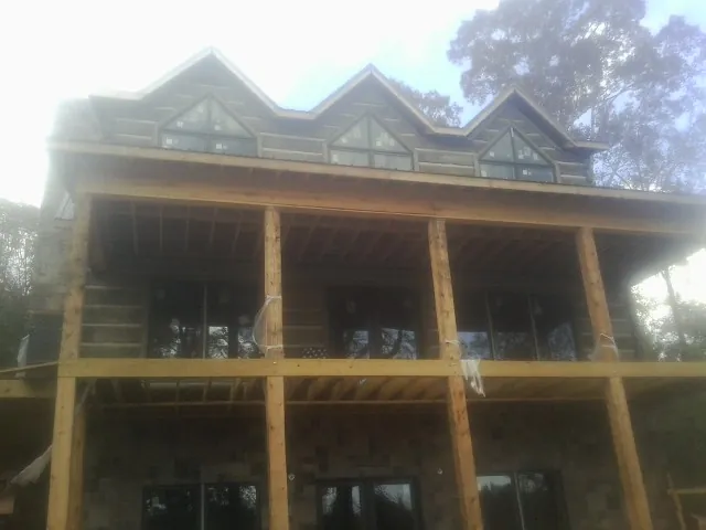 Dormers and porch framing on a large log home under construction — Roof Coating work by our crew in Holmen