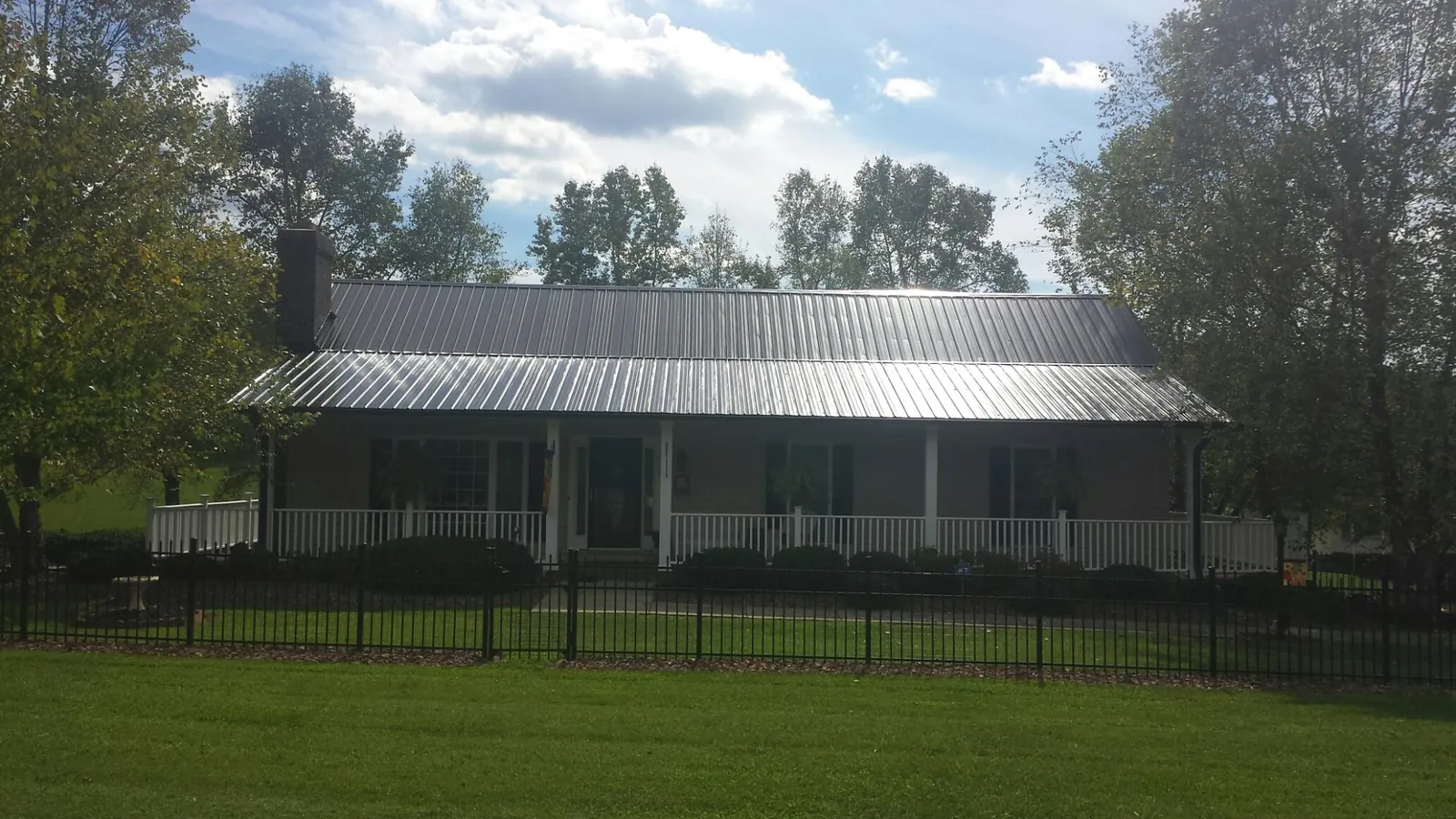 Gray metal roof on a brick ranch with a full width front porch — Gutter Guard Installation work by our crew in Holmen