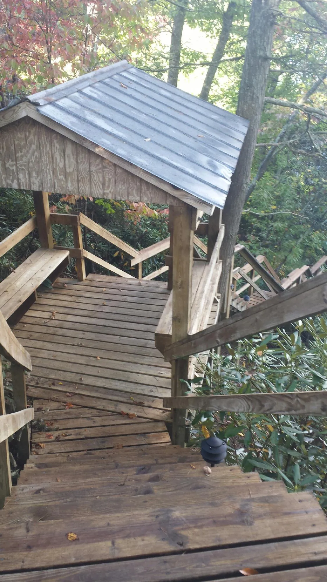 Metal roofed shelter over wooden steps on a wooded walkway — Skylight Repair & Installation work by our crew in Holmen